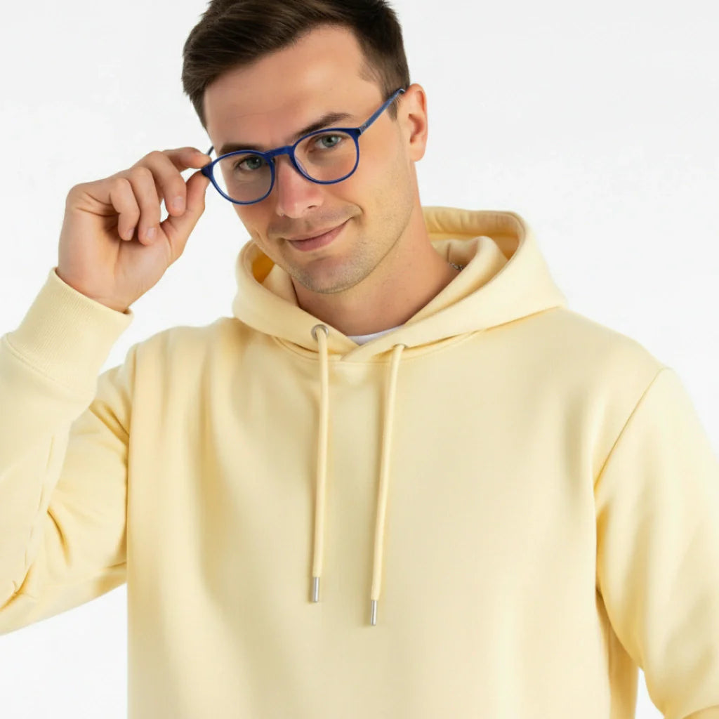 Homem usando óculos de grau azuis com hoodie amarelo claro, estilo moderno e confortável