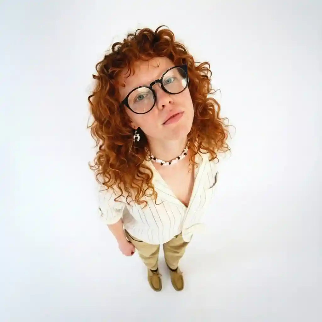 Mulher com óculos de grau redondos e cabelo cacheado, estilo moderno e elegante